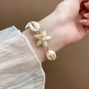 Close-up of a beach-style ceramic starfish and shell beaded bracelet on a wrist.