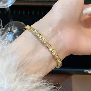 Détail d'un bracelet jonc en zircon plaqué or 18 carats au poignet avec des paillettes.