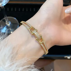 Détail d'un bracelet à maillons entrelacés en oro 18 carats avec zircons sur le poignet