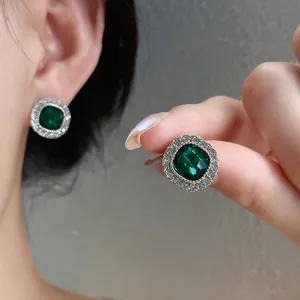Primo piano di eleganti orecchini a lobo rotondi verde smeraldo con ago d'argento e strass luminosi