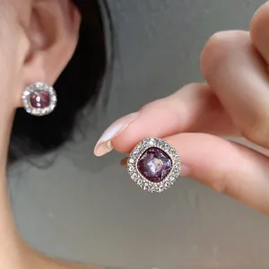 Dettaglio di eleganti orecchini a lobo tondi in argento con gemma viola e strass