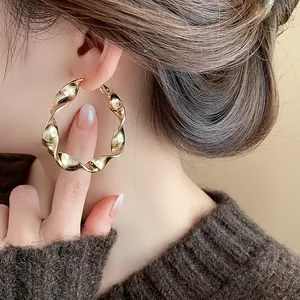 Gold twisted spiral hoop earrings worn by model showing elegant high-end fashion design