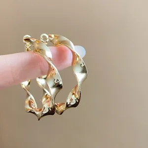 Close-up view of golden twisted spiral hoop earrings with metallic luster