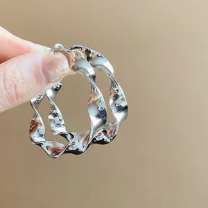 Close-up of silver twisted spiral hoop earrings showing metallic texture and unique design.