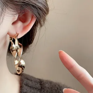 Detailed close-up of gold twisted spiral hoop earrings worn by a model for a stylish look