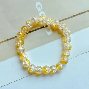 Dettaglio di un braccialetto di perle di cristallo screpolate gialle e trasparenti