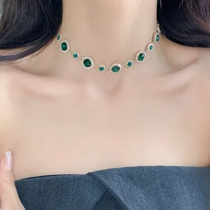 Vista dettagliata di un'elegante collana girocollo d'oro con pietre verde smeraldo sul modello
