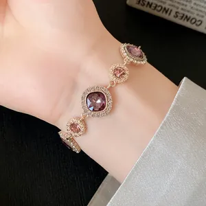 Dettaglio di un elegante bracciale dorato con cristalli viola su un polso femminile