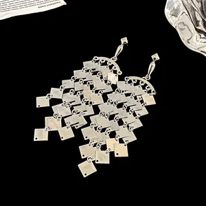 Gros plan de boucles d'oreilles pendantes à pampilles en sequins argentés en losange.