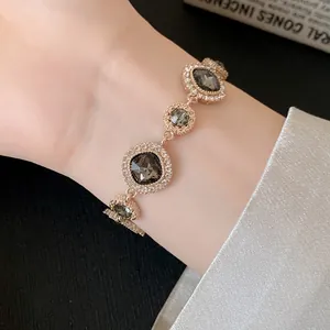 Primo piano di un bracciale in oro rosa con cristalli grigio scuro e strass bianchi