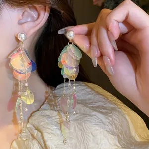 Détail de boucles d'oreilles longues à glands en paillettes irisées avec perles