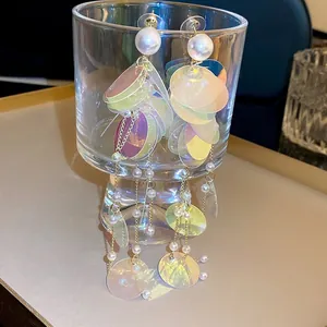 Détail de boucles d'oreilles à pampilles avec paillettes irisées et perles sur un verre