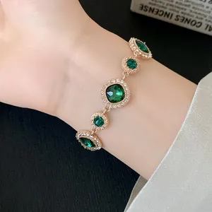 Primo piano di un elegante bracciale in oro con pietre verde smeraldo e diamanti