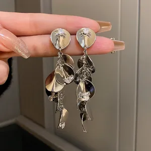 Détail de boucles d'oreilles pendantes argentées avec sequins et zircons brillants