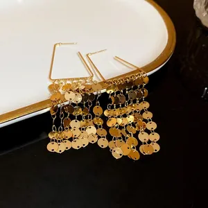 Gros plan de boucles d'oreilles dorées à paillettes avec de longues franges