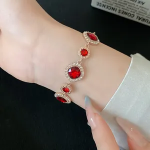 Vista dettagliata di un elegante bracciale in oro con pietre preziose rosse sul polso