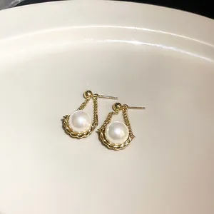 Detailansicht eleganter goldener Perlenohrstecker mit strukturiertem Kettenrahmen