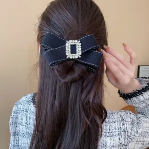 Close-up of elegant black velvet bow hair clip with rhinestone center on long hair