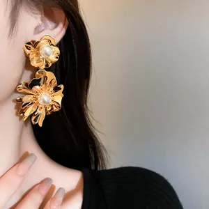Nahaufnahme eleganter goldfarbener Blumenohrringe mit einer zentralen Perle verziert