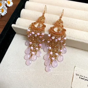 Orecchini boho dorati con perline di vetro rosa e pietre a goccia sfaccettate.