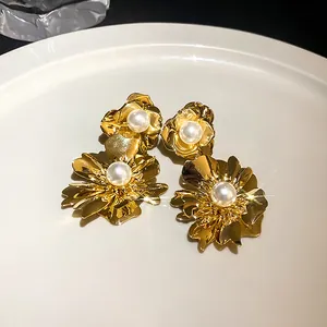 Detailansicht eleganter goldener Blumenohrringe mit weißen Perlenakzenten in der Mitte