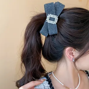 Close-up of elegant grey denim bow hair clip with rhinestone buckle worn in ponytail