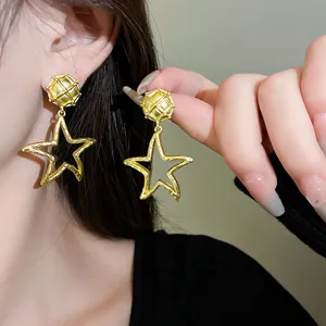 Detailansicht goldener geometrischer Sternohrringe am Ohr eines Models mit mattem Finish