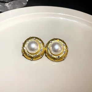 Nahaufnahme goldener Ohrstecker mit zentraler Perle und funkelnden Zirkonia-Akzenten