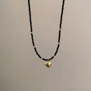 Gros plan d'un collier minimaliste avec des perles de cristal noires et pendentif coeur