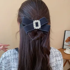 Detailed view of the black rhinestone bow hair clip styled in a partial bun hairstyle