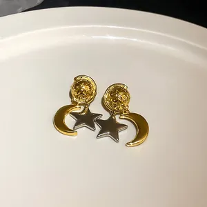Nahaufnahme von eleganten Gold- und Silber-Stern- und Mondohrringen auf weißem Teller.