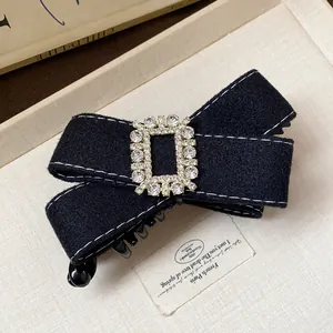 Close-up of elegant black fabric bow hair clip with sparkling crystal buckle detail