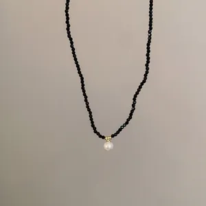 Gros plan d'un collier de perles en cristal noir avec un élégant pendentif perle