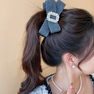 Detailed macro view of a grey denim bow hair clip with a sparkling rhinestone buckle