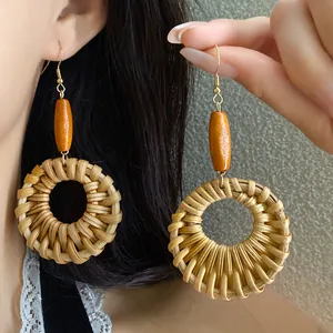 Detailed macro view of ethnic woven rattan hoop earrings with orange wood beads