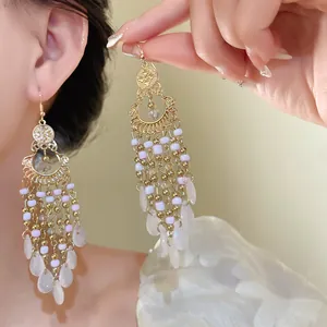 Dettaglio di raffinati orecchini pendenti boho con perline di vetro e metallo dorato