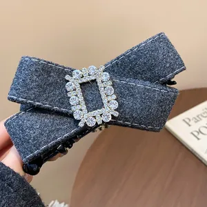 Close-up of elegant grey felt bow hair clip with sparkling rhinestone buckle