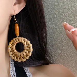 Close-up detail of ethnic style woven round earrings with orange wood bead on female model
