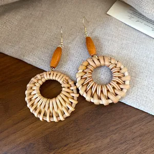 Detailed view of bohemian style hand-woven rattan hoop earrings with wooden bead accents.