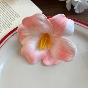 Primo piano di un fermaglio per capelli a fiore in schiuma rosa e bianco con texture morbide.