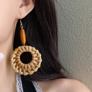 Detail shot of ethnic style rattan woven hoop earrings with a wooden bead accent
