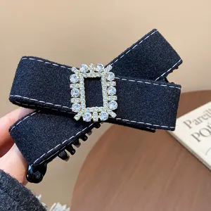 Close-up of black fabric bow hair clip with a sparkling rectangular rhinestone buckle