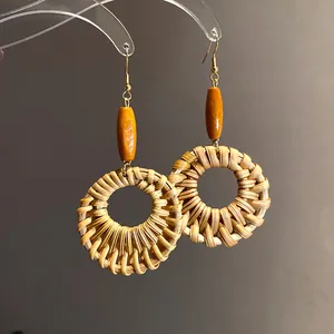 Detail view of ethnic style woven rattan circular drop earrings with orange wooden beads