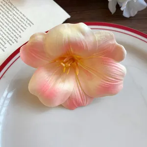 Primo piano di una molletta per capelli a fiore in schiuma sfumata pesca su un piatto