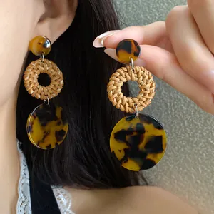 Close-up detail of boho handmade rattan woven earrings featuring vintage leopard resin discs