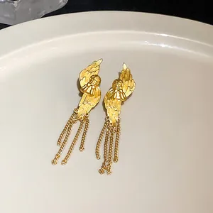 Detailansicht goldener Engelsflügel mit feinen Federstrukturen und hängenden Metallketten.