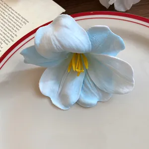 Dettaglio macro di una molletta per capelli a fiore in schiuma azzurra con petali soffici