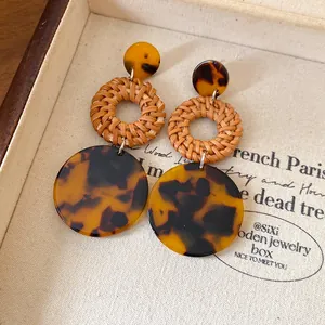 Close-up of vintage bohemian rattan woven earrings with tortoiseshell resin discs
