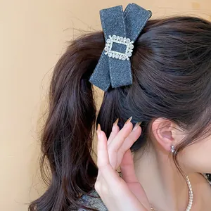 Detailed view of an elegant dark grey fabric bow hair clip with a sparkly rhinestone buckle