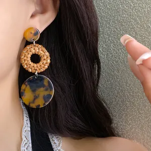 Close-up of bohemian woven rattan earrings with tortoiseshell pattern discs
